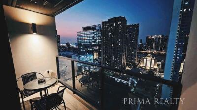 City view from high-rise apartment balcony at dusk with outdoor seating