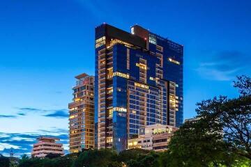 Modern high-rise residential building at dusk with illuminated windows