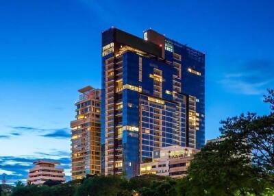 Modern high-rise residential building at dusk with illuminated windows