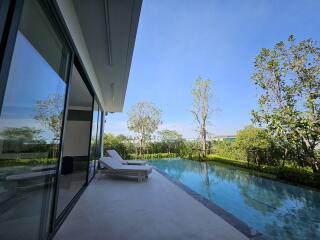 Luxurious outdoor pool area with sun lounger and greenery