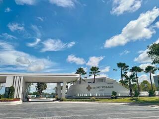 Modern residential building entrance with lush landscaping under a clear blue sky