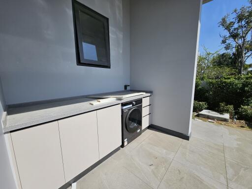 Modern outdoor laundry area with washer and ample cabinet space