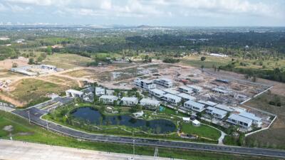 Aerial view of a developing residential area with modern houses and landscaped pond