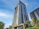 Modern high-rise residential building with clear blue sky and greenery