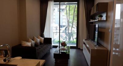 Modern living room with sofa and entertainment unit, with a large window overlooking greenery