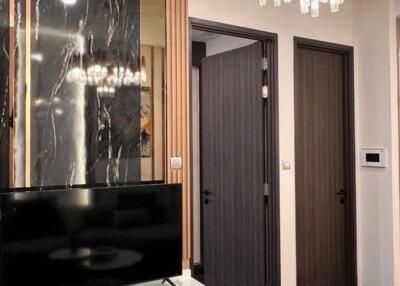 Elegant living room with modern black marble-decoration, flat-screen TV, and detailed wooden doors