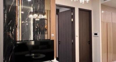 Elegant living room with modern black marble-decoration, flat-screen TV, and detailed wooden doors