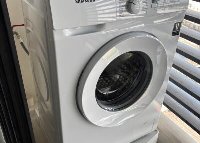 Samsung washing machine in a well-lit laundry area with balcony