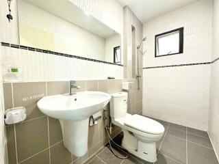 Modern clean bathroom interior with a white sink, toilet, and tiled walls