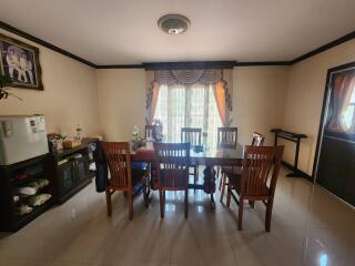 Spacious dining room with a large wooden table and chairs, well-lit by natural light