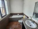 Spacious bathroom with tub and wooden flooring