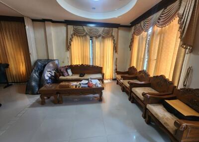 Spacious living room with ornate wooden furniture and elegant curtains