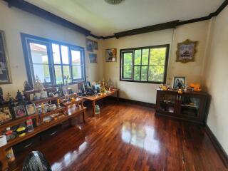 Spacious living room with polished wooden floors and large windows facing greenery