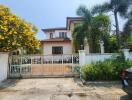 Elegant two-story house with a lush garden and secure gate