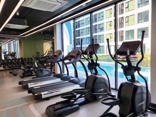 Modern gym with treadmills and elliptical machines in a residential building