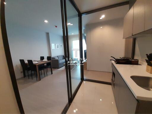 Modern apartment interior with kitchen and dining area visible through large glass door