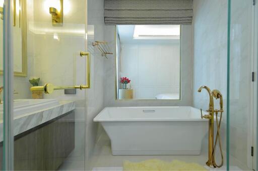 Elegant bathroom with a freestanding white bathtub, golden fixtures, and modern design