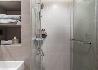 Modern bathroom interior with a glass shower, large tiles, and stylish storage shelves