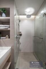 Modern bathroom interior with a glass shower, large tiles, and stylish storage shelves