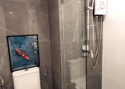 Modern bathroom with wall-mounted toilet, glass shower, and gray tiles
