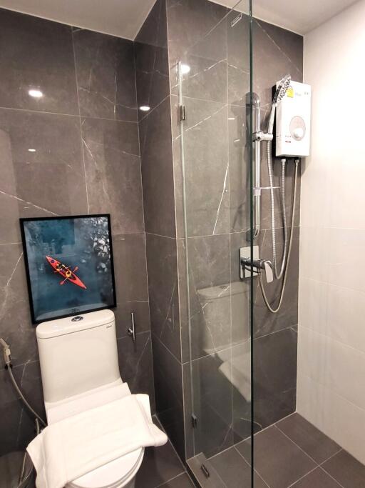 Modern bathroom with wall-mounted toilet, glass shower, and gray tiles