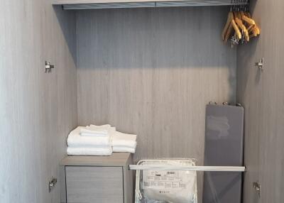 Well-organized storage closet with shelving, ironing board, and clothing items