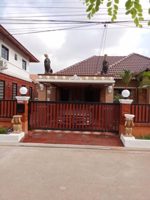 Exterior view of a residential house with red roof and secured gate