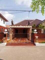 Elegant residential home exterior with detailed roof design and gated entrance