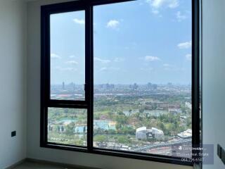 Spacious bedroom with large windows overlooking the city skyline