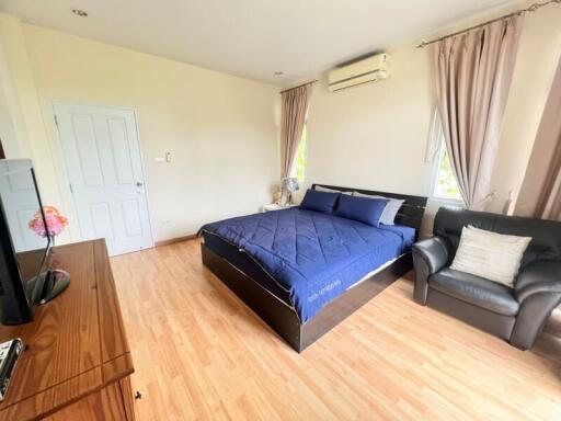 Spacious bedroom with wooden flooring, large bed, and comfortable seating area