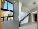 Modern spacious living room with large windows and a staircase