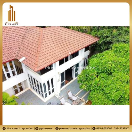 Aerial view of a spacious two-story residential house with terracotta roof tiles surrounded by lush greenery