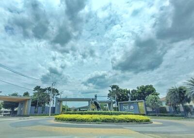 Cloudy sky over a gated community entrance with landscaped roundabout