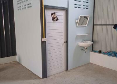 Compact interior utility room with white door, security window, and external sink