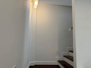 Brightly lit staircase with white walls and wooden steps