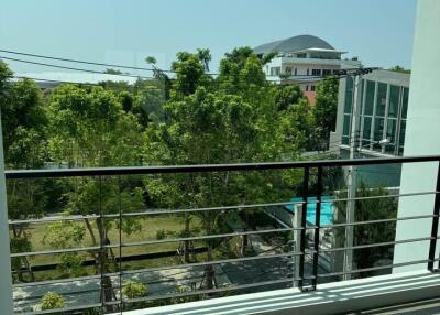 Sunny balcony overlooking lush greenery and distant buildings