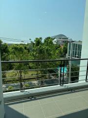 Sunny balcony overlooking lush greenery and distant buildings