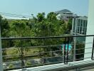 Sunny balcony overlooking lush greenery and distant buildings