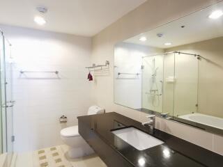 Modern bathroom with well-lit vanity, large mirror, and glass shower