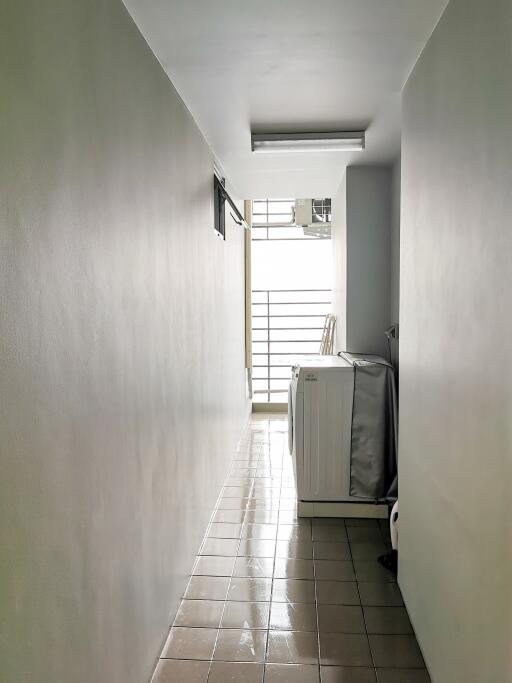 Bright and narrow corridor with tiled floor and window at the end