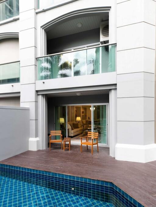 Exterior view of a residential building showing a swimming pool and an open patio leading to a cozy indoor living space
