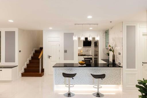Modern open kitchen with bar seating, elegant lighting, and adjacent living area
