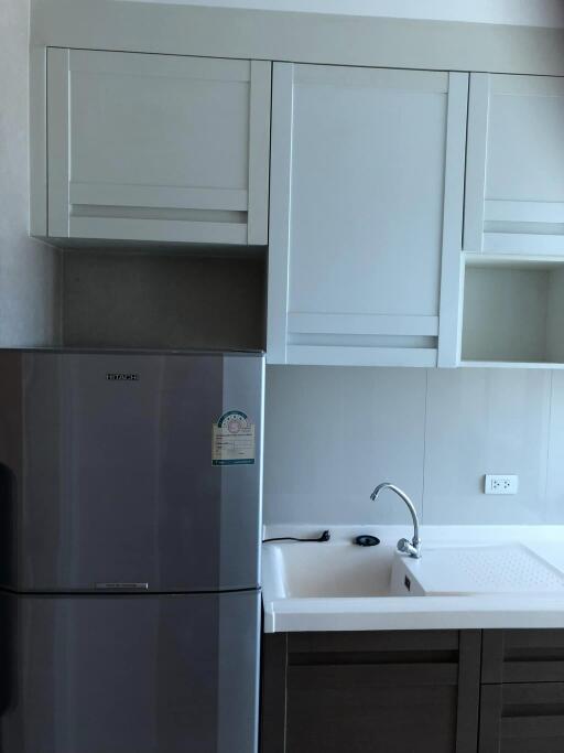 Modern kitchen with white cabinetry and stainless steel refrigerator