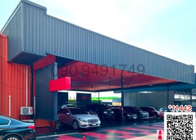Modern commercial building exterior with cars parked under canopy