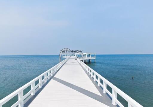 White wooden pier extending into the clear blue ocean under a bright sky