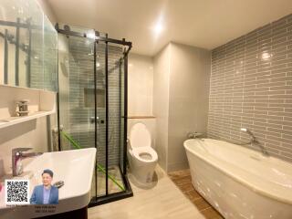 Modern bathroom with a glass-enclosed shower, bathtub, and toilet