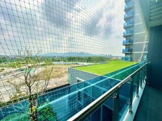 Spacious balcony with protective netting overlooking a scenic green landscape and a distant urban area