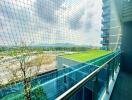 Spacious balcony with protective netting overlooking a scenic green landscape and a distant urban area