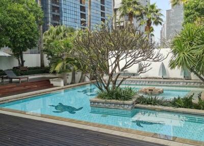 Luxurious outdoor swimming pool surrounded by lush gardens and modern skyscrapers