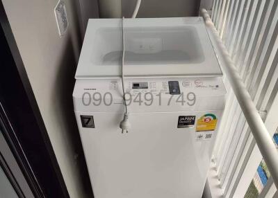 Compact white top-loading washing machine in a narrow laundry space